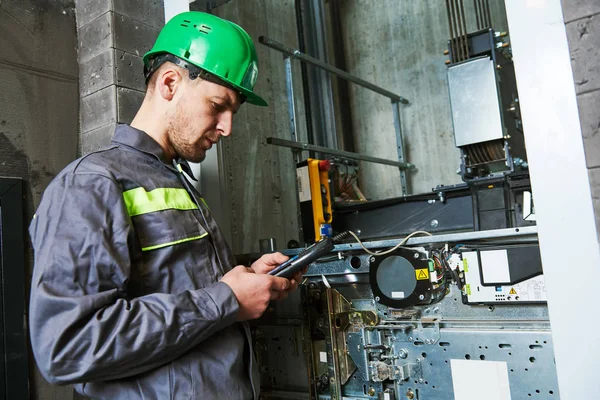 Ascensoriste intervenant seul en local machinerie, consultant un appareil de mesure
